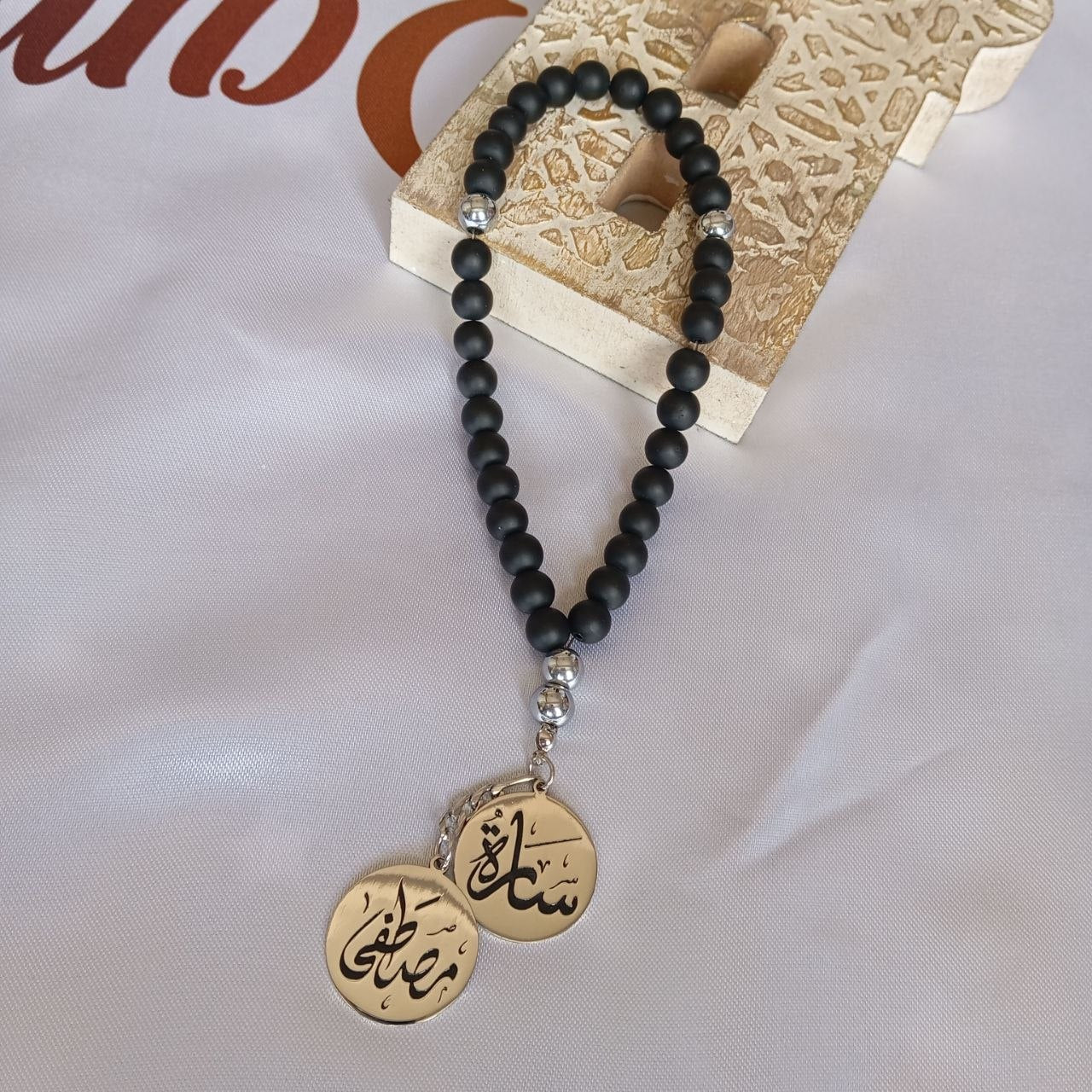 Black beaded necklace with gold pendants on a textured surface
