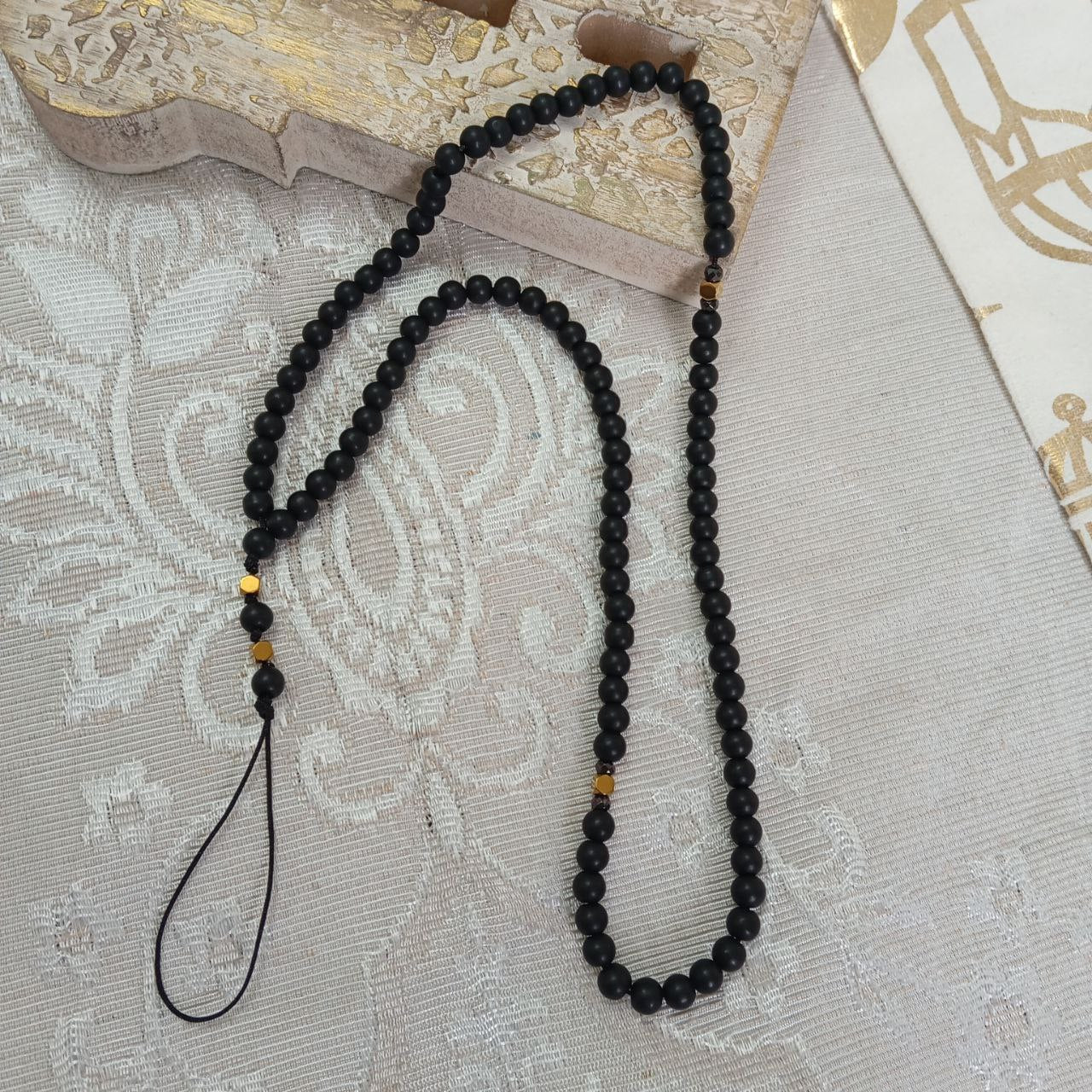 Black beaded necklace on a textured surface