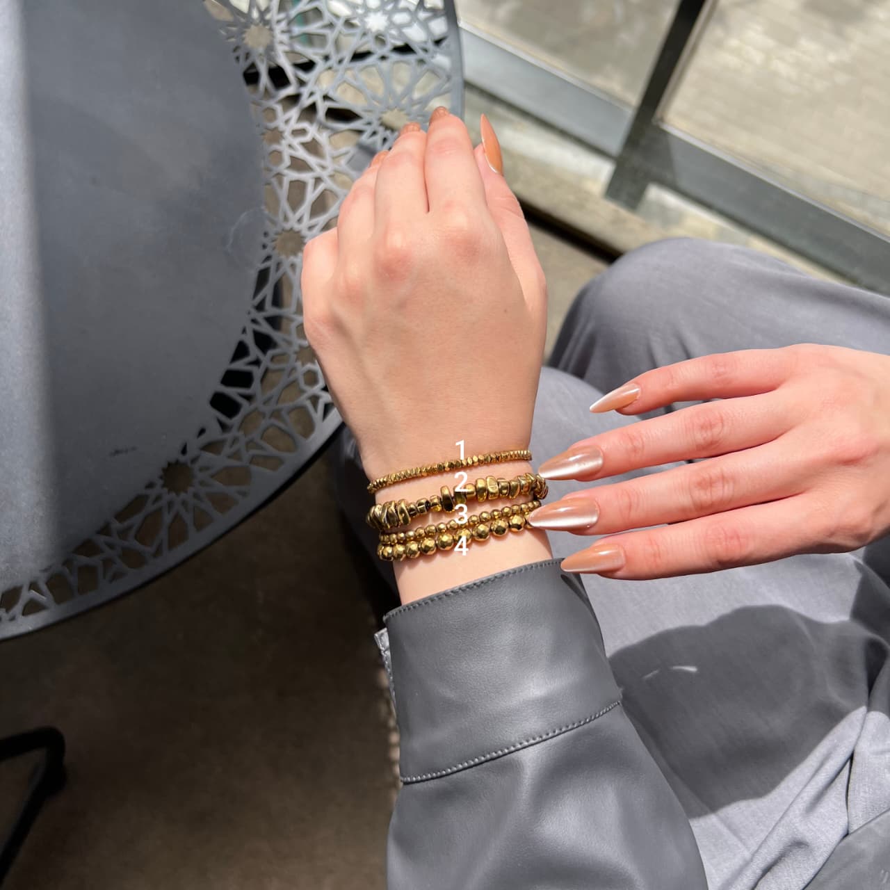 Hand wearing gold bracelets with a decorative background