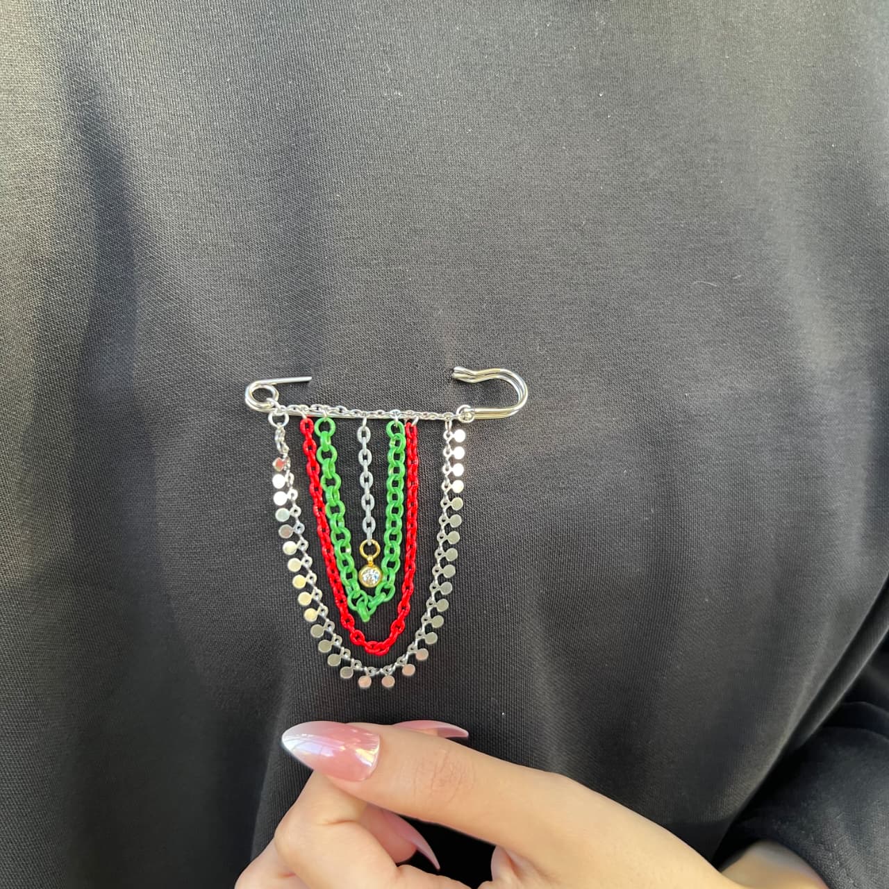 Colorful chain brooch on a dark fabric background