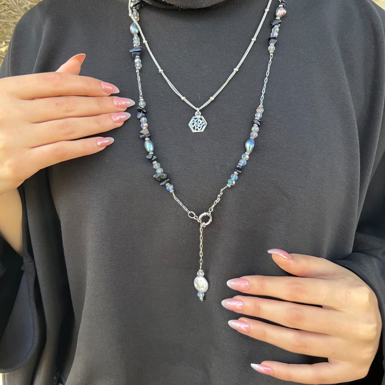 Necklace with beads and a pendant worn by a person against a dark background