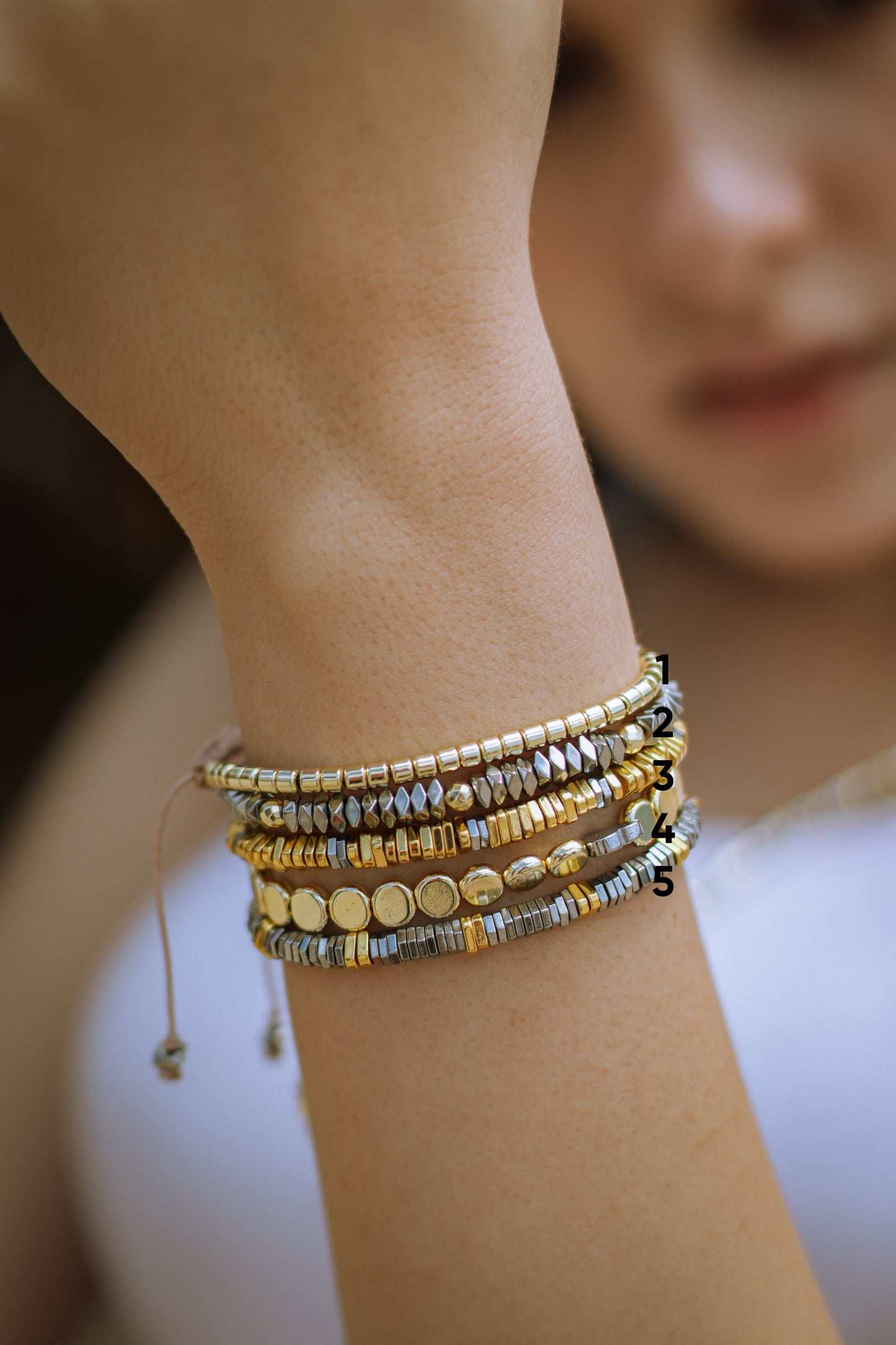 Close-up of a wrist wearing multiple beaded bracelets with a blurred background