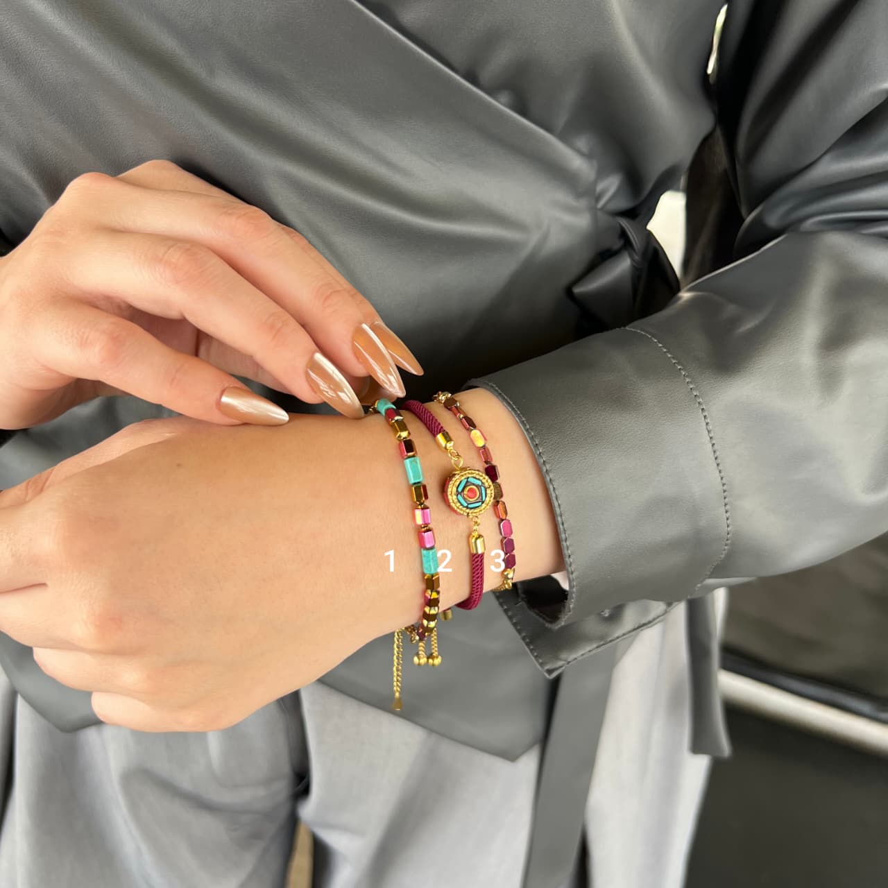 Person wearing colorful bracelets on a gray jacket background