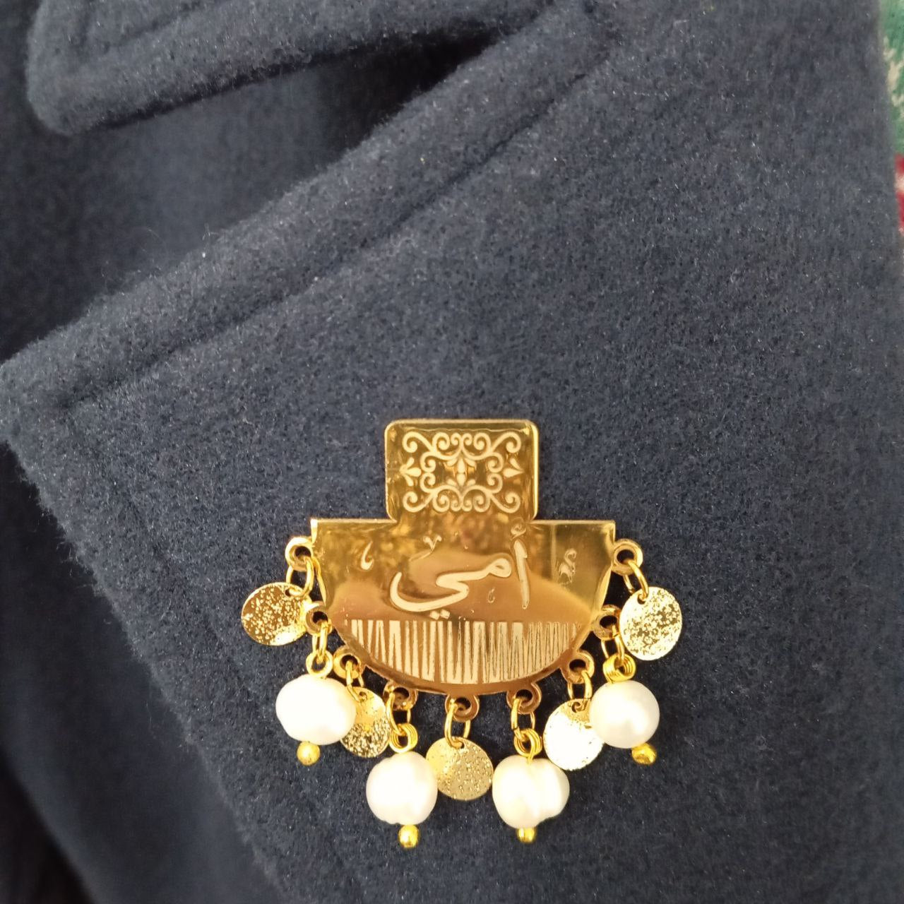 Gold brooch with white stones on a dark fabric background