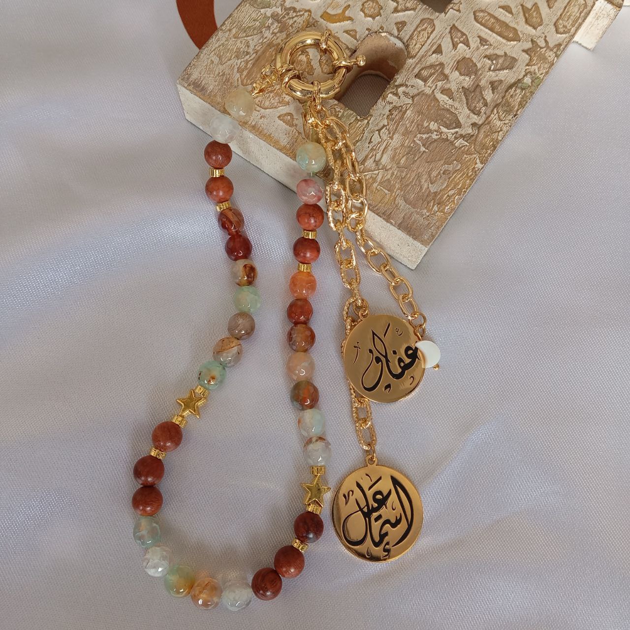 Beaded keychain with gold charms on a textured surface