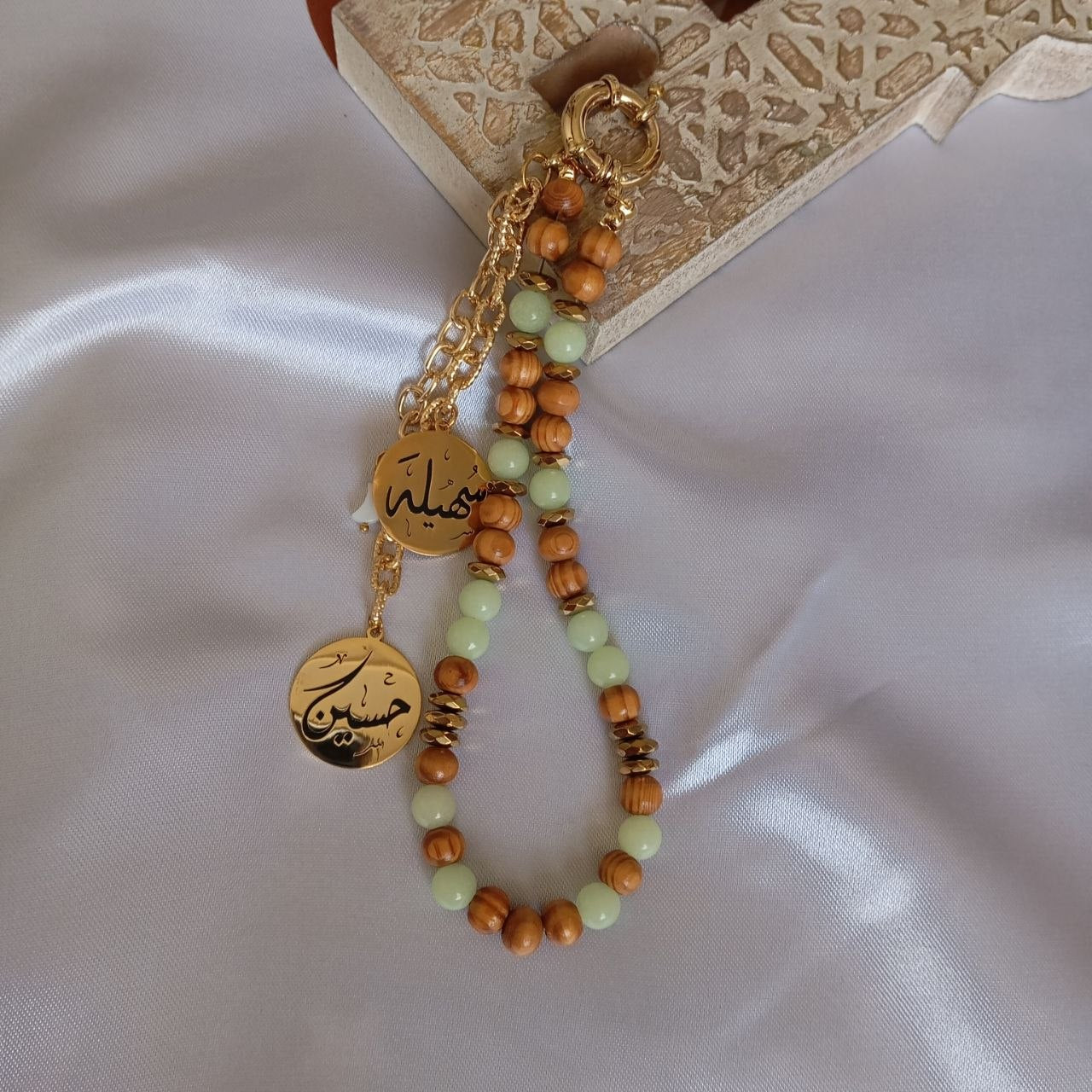 Beaded bracelet with gold charms on a textured surface