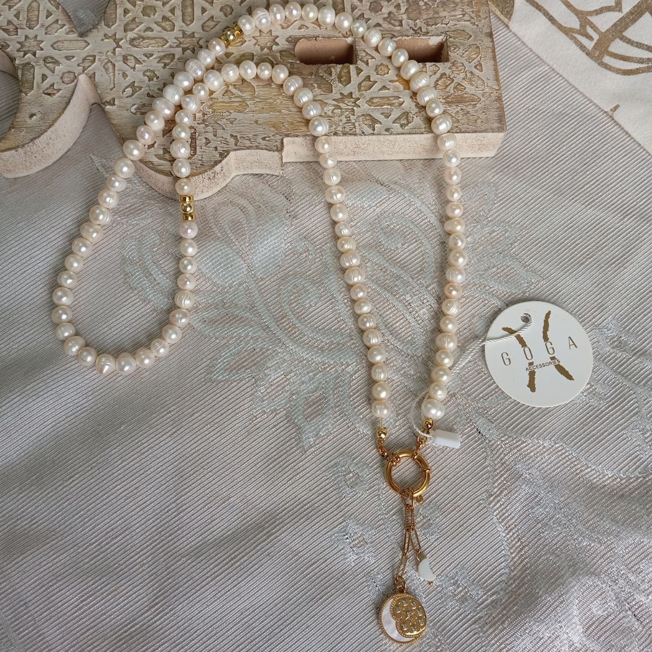 Pearl necklace with gold accents on a textured surface