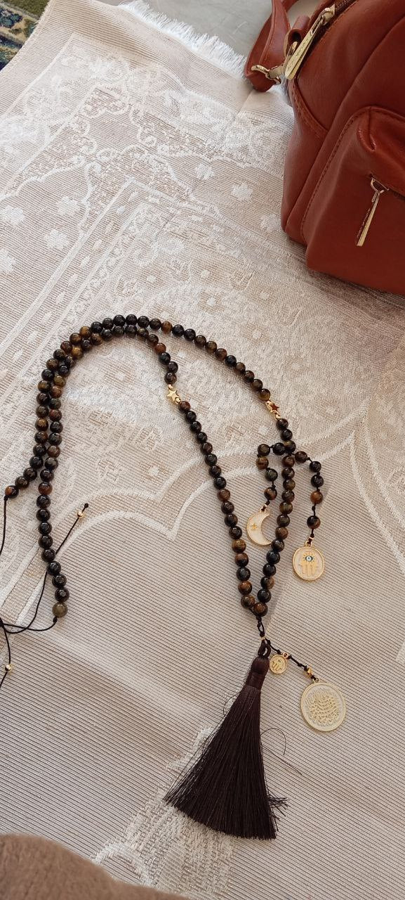 Brown beaded necklace with tassel on a textured surface