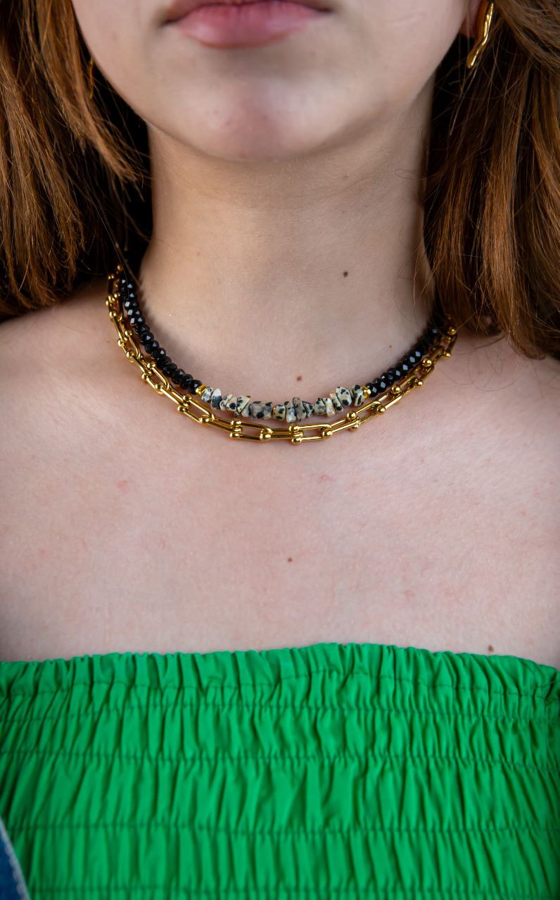 Necklace with black and gold beads worn by a person with green top