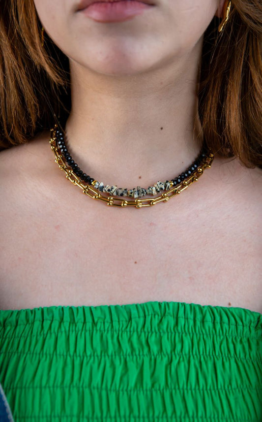 Necklace with black and gold beads worn by a person with green top