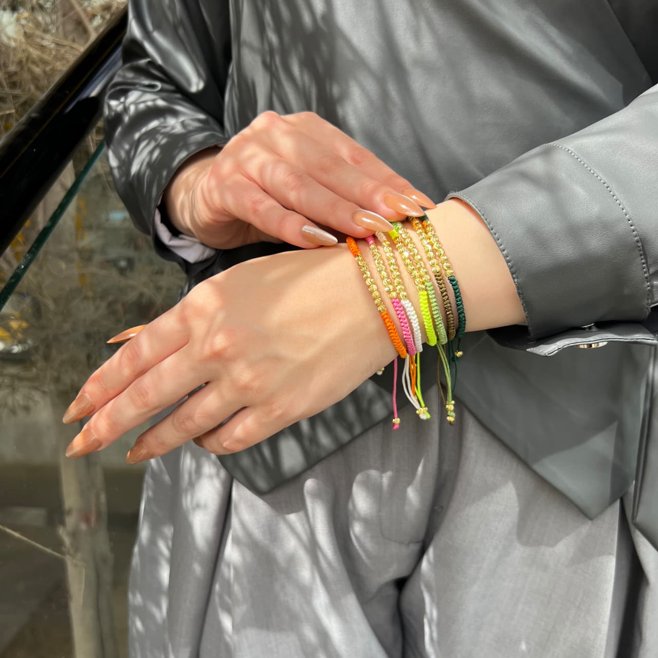 Person wearing colorful bracelets on a gray jacket background