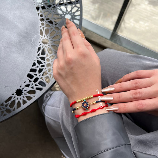 Person wearing two bracelets on a gray chair with a decorative table