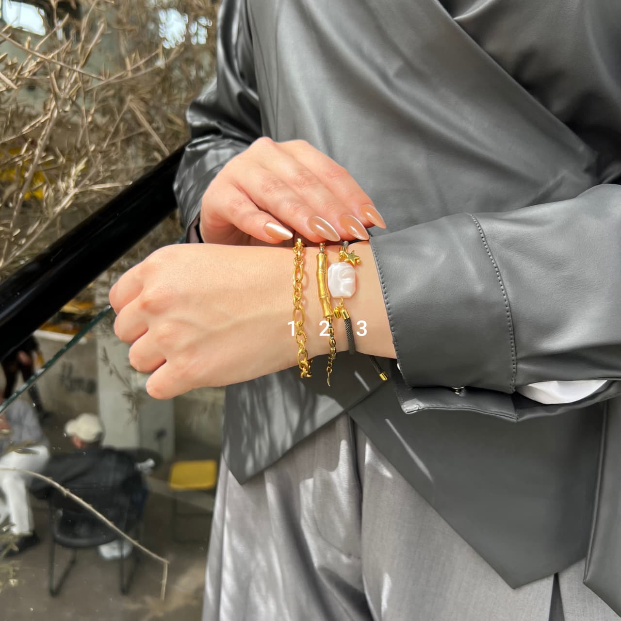 Person wearing multiple bracelets on a gray background