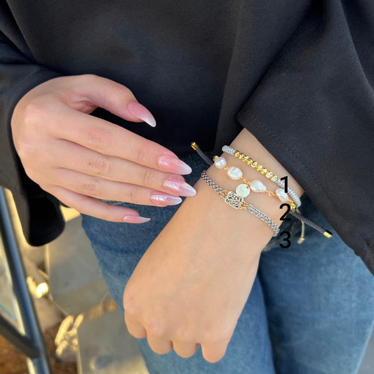 Close-up of a person's wrist with multiple bracelets on a blurred background