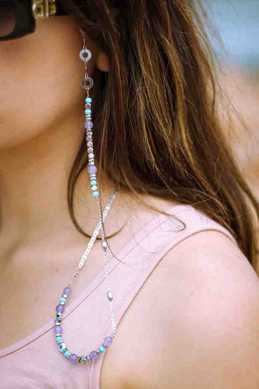 A woman wearing a gold-colored necklace with multicolored stone beads.