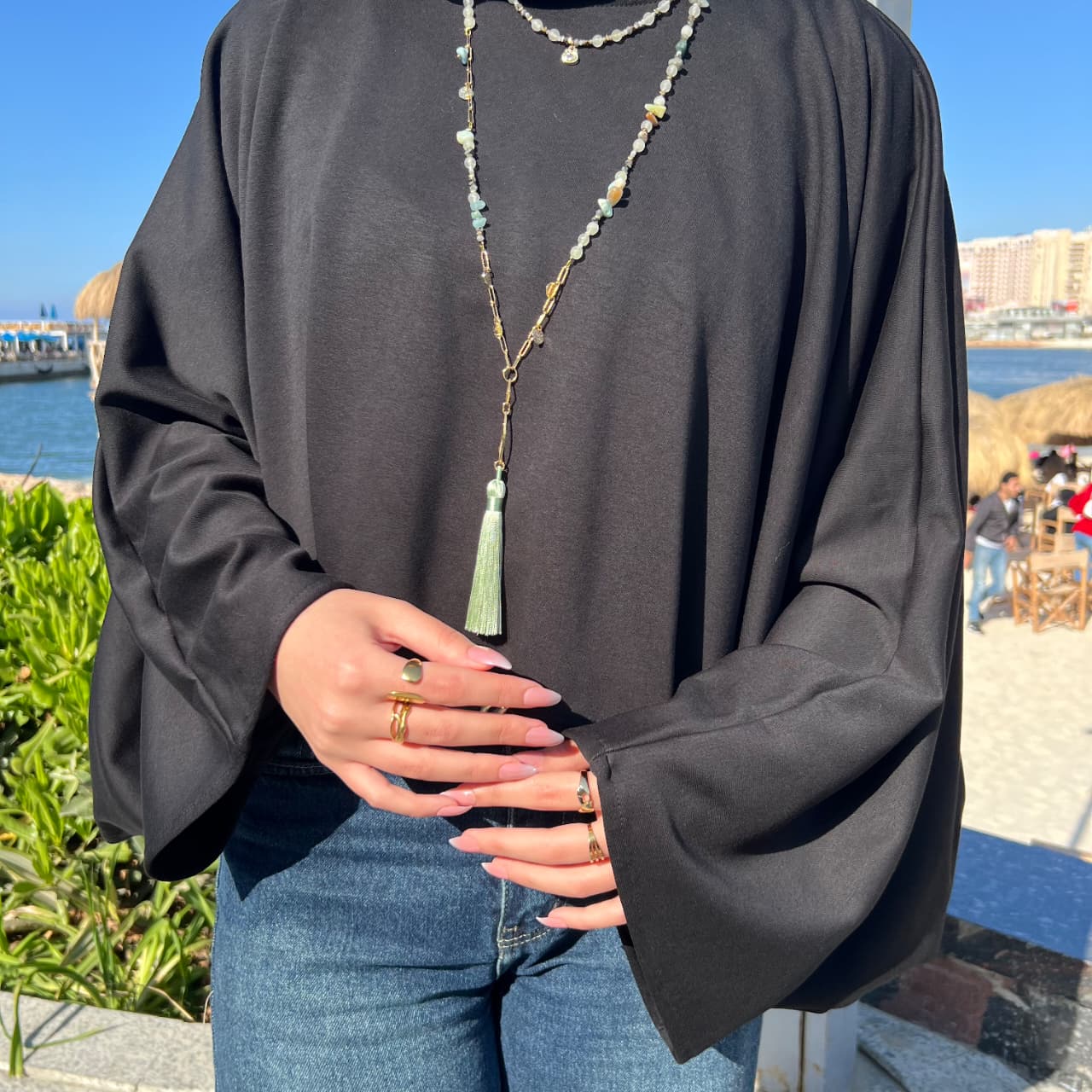 Person wearing a black long-sleeve top and blue jeans with a scenic background