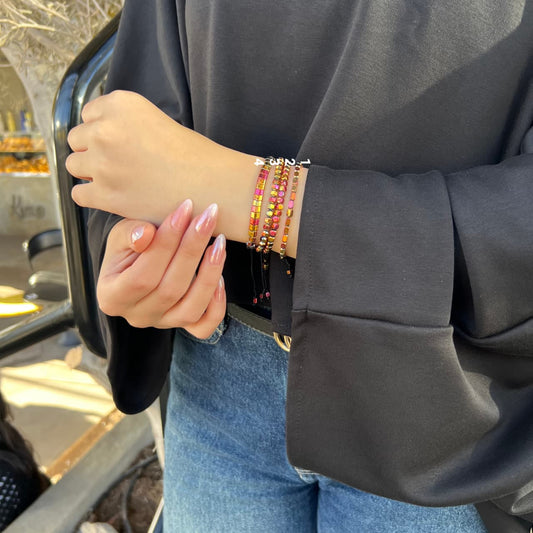 Person wearing colorful bracelets on a blurred background