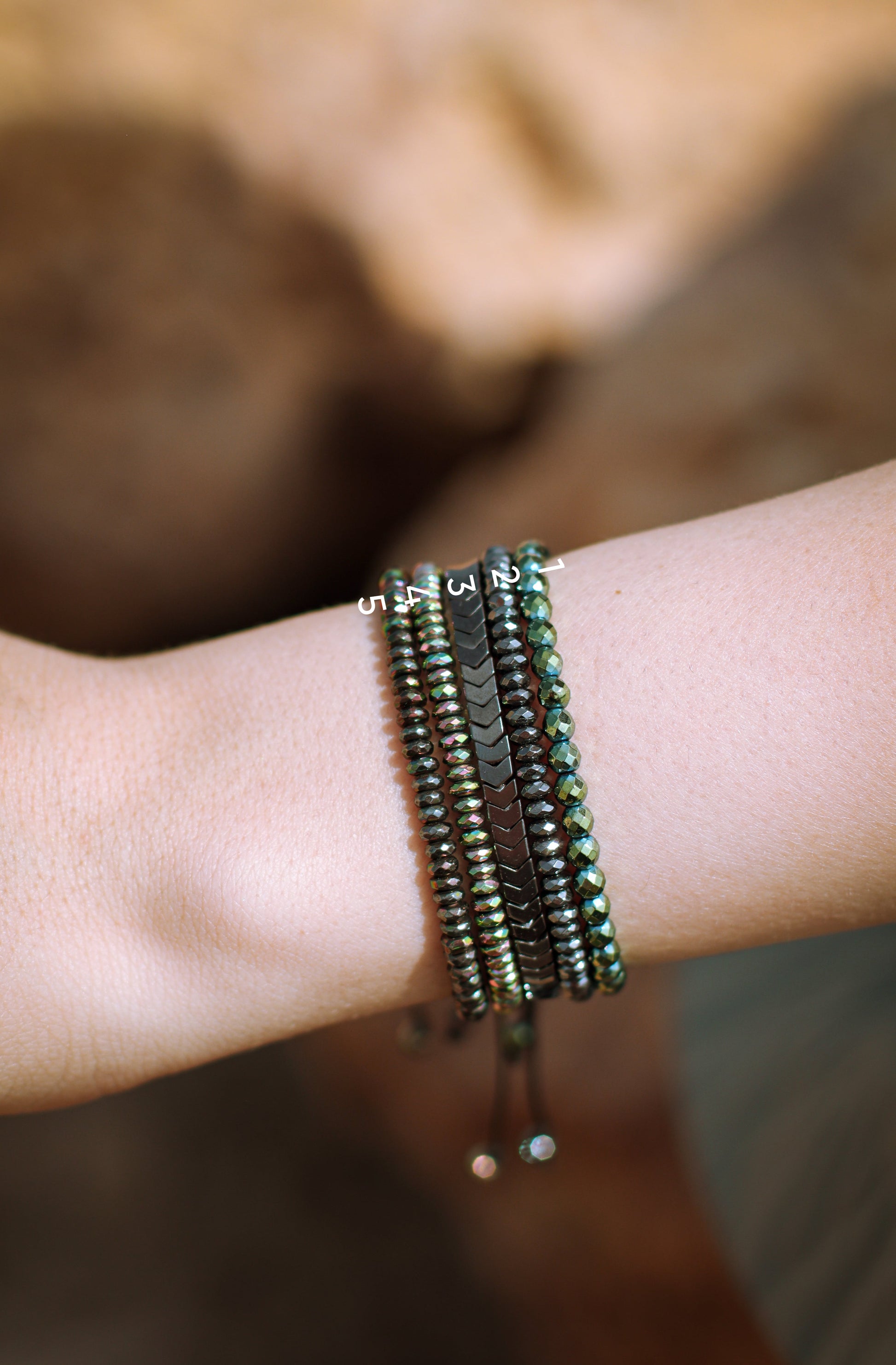 Close-up of a wrist wearing multiple beaded bracelets with a blurred natural background