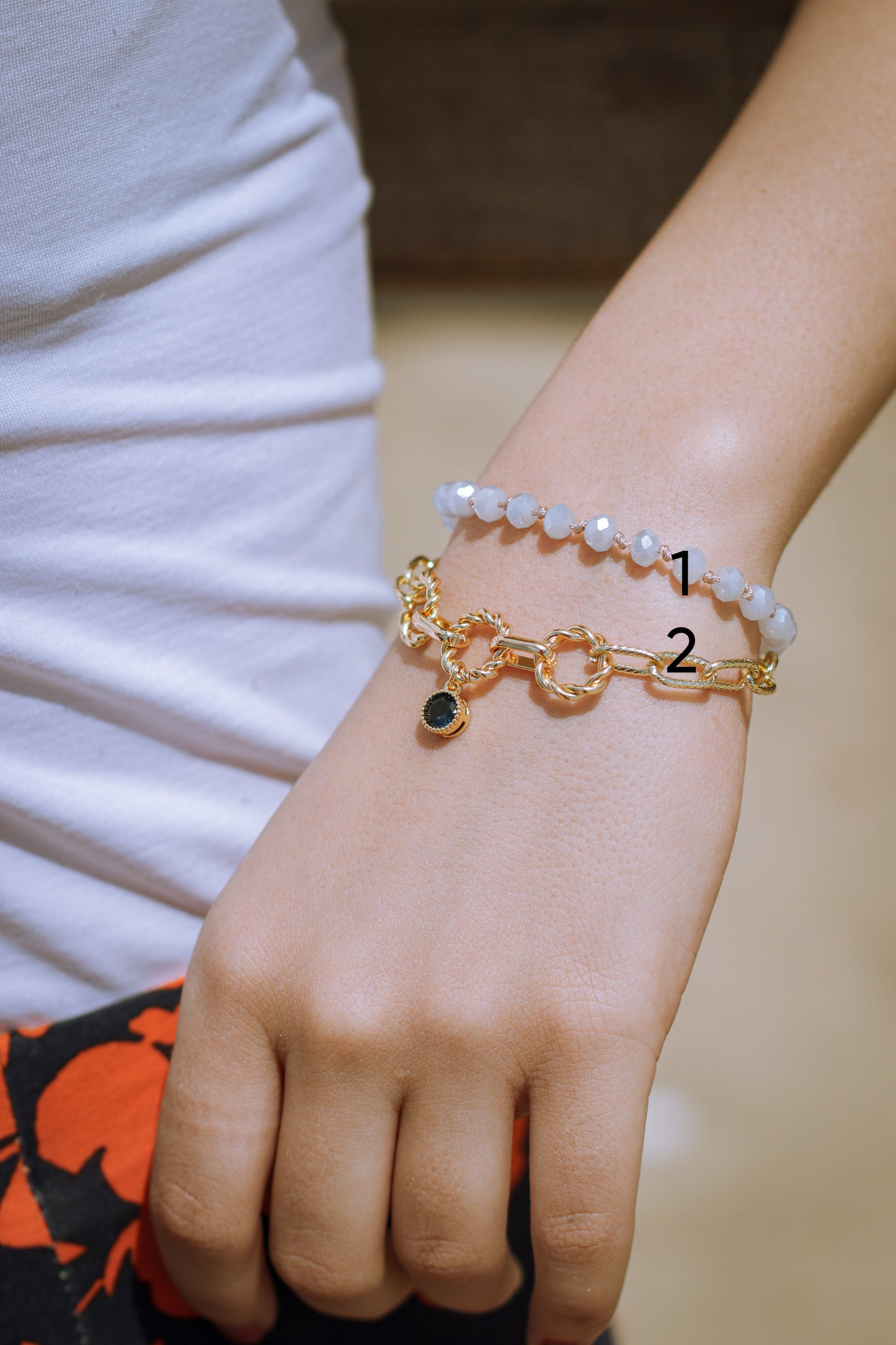 Gold bracelet with a black gemstone on a wrist against a neutral background