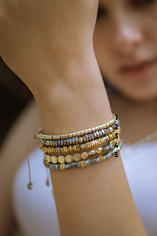 Close-up of a wrist wearing multiple beaded bracelets with a blurred background