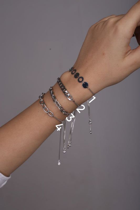 Hand wearing multiple bracelets on a gray background