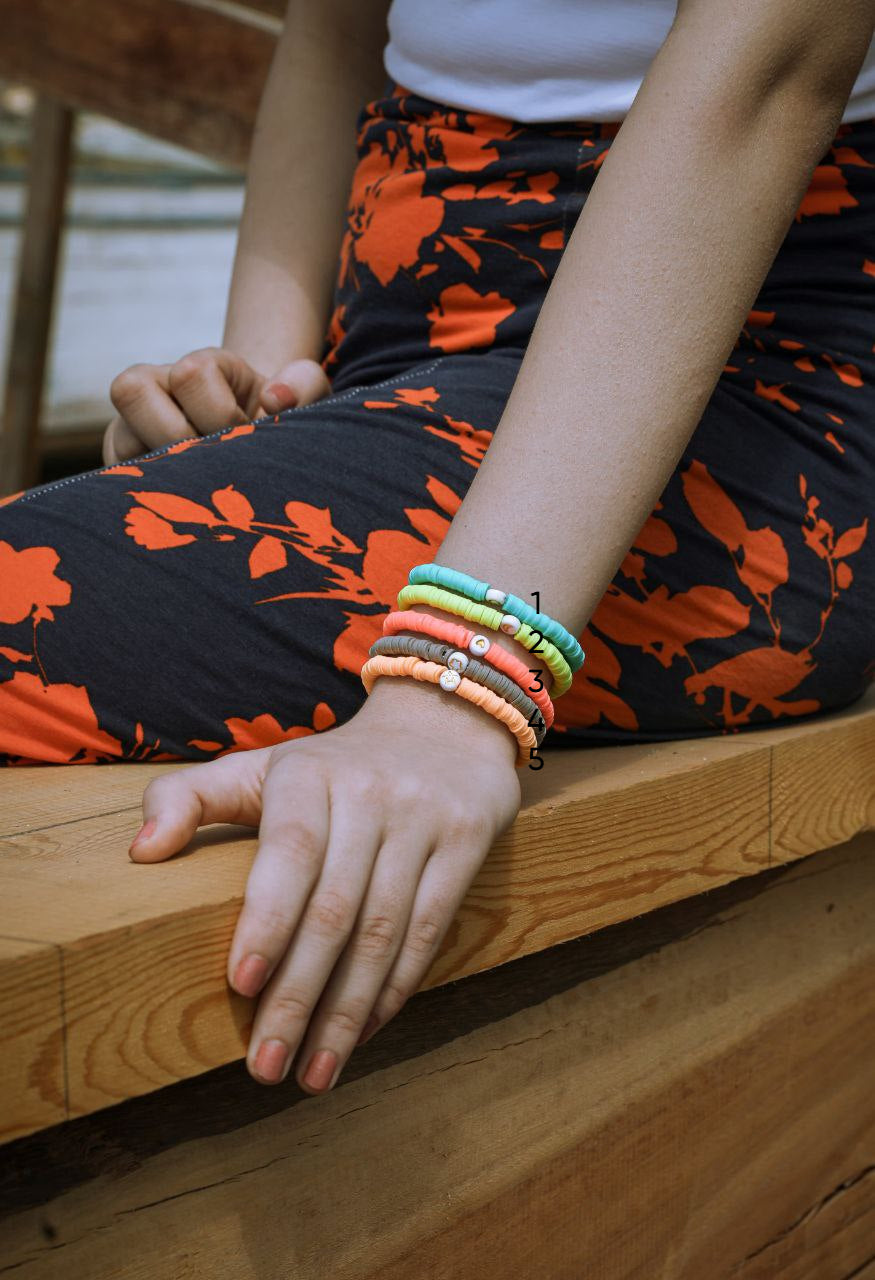 Person wearing colorful bracelets on a wooden surface