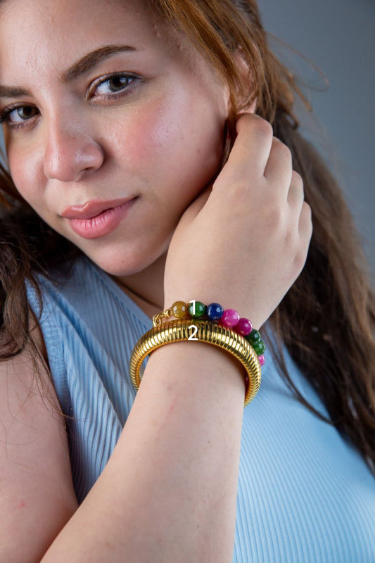 Woman wearing a colorful bracelet on her wrist against a neutral background