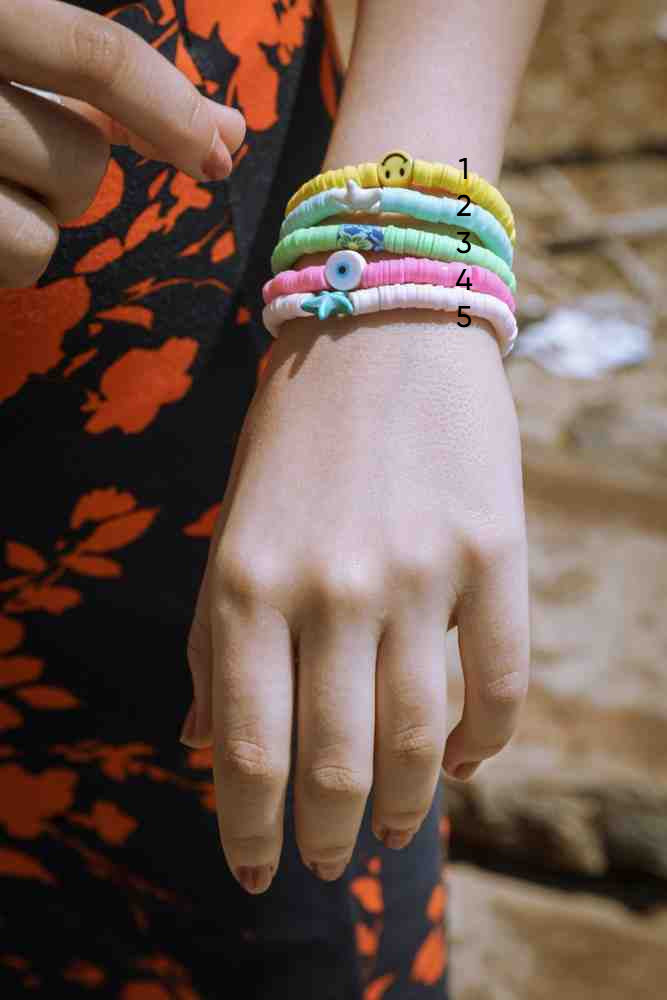 Hand wearing colorful bracelets with decorative elements on a blurred background