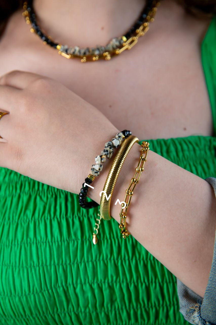 Close-up of a person's arm wearing gold bracelets with a green top.