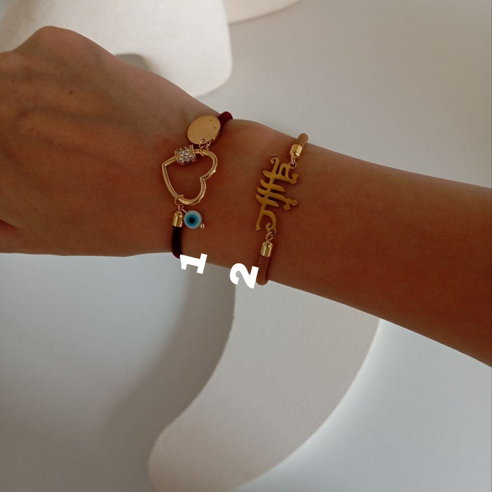 Close-up of a wrist wearing multiple gold bracelets with various designs on a neutral background