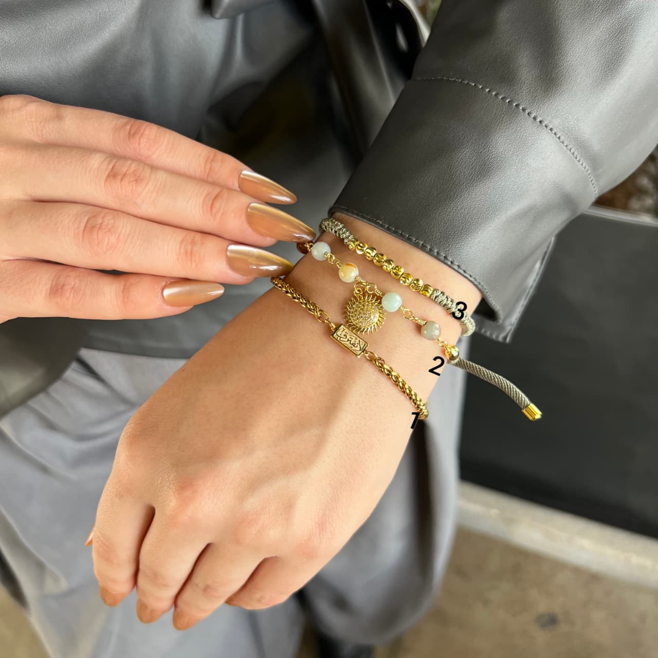 Close-up of a person's wrist with multiple gold bracelets on a gray background