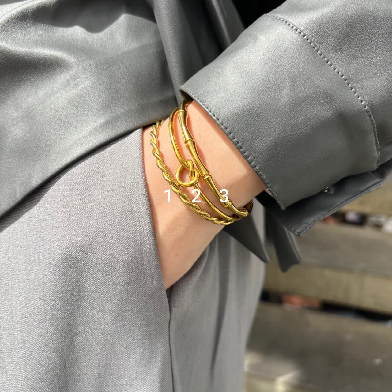Gold bracelets on a person's wrist with a blurred background